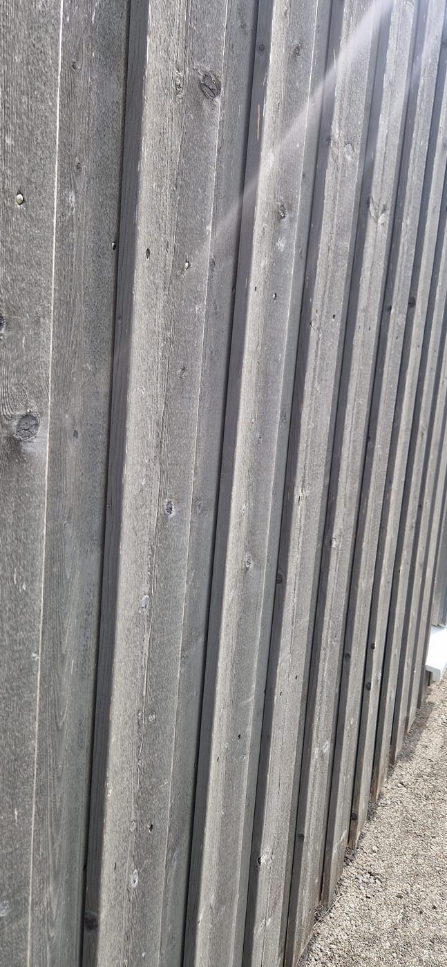 Vorvergraute vertikale Holzschalung des Bestandsgebäudes im Detail